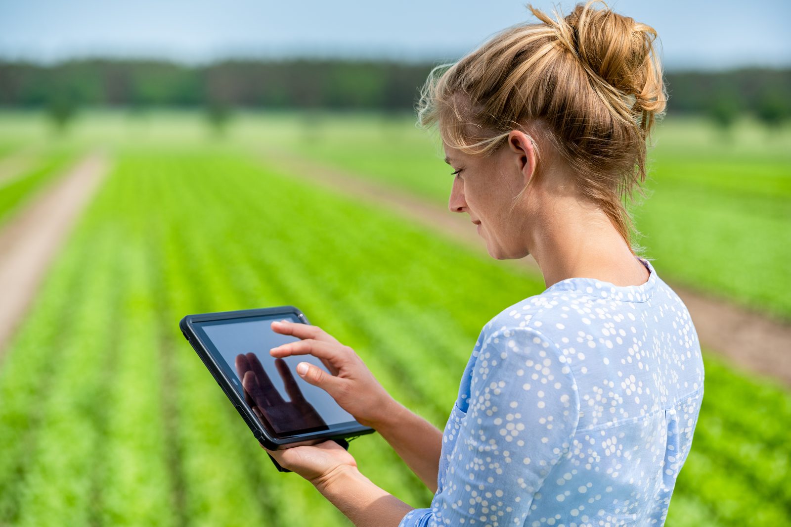 Mitarbeiterin prüft Daten auf einem Tablet im Außeneinsatz